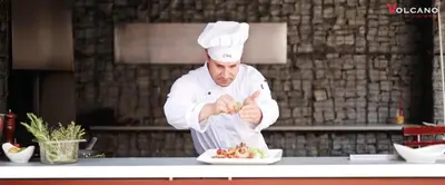 a chef preparing a plate of food in a kitchen at Volcano Spa Hotel in Prague