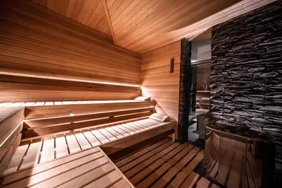 an empty wooden sauna with a stone wall at Volcano Spa Hotel in Prague