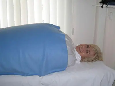 a woman laying in a hospital bed with a pillow at Lazensky Hotel Park in Poděbrady