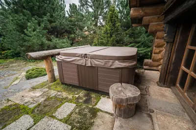 a hot tub with a cover sitting next to a stump at Luxusní srub Líny in Bukovno