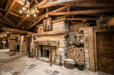 a large stone fireplace in a room with wooden ceilings at Luxusní srub Líny in Bukovno