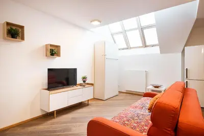 a living room with an orange couch and a tv at Rehorova apartments by Pragueforyou in Prague