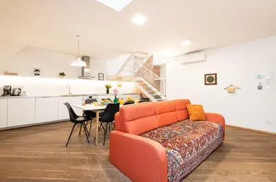 a living room with an orange couch and a kitchen at Rehorova apartments by Pragueforyou in Prague