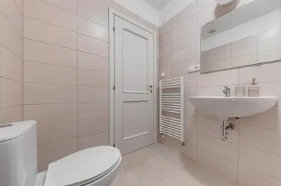a white bathroom with a toilet and a sink at Vita Nejedleho apartments in Prague