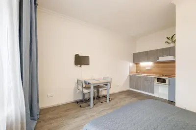 a bedroom with a small table and a kitchen at Vita Nejedleho apartments in Prague