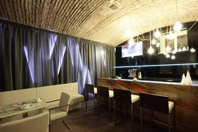 a restaurant with a bar with chairs and purple curtains at Pure White in Prague
