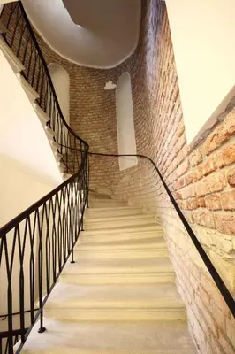 a staircase with a brick wall and black railings at Pure White in Prague