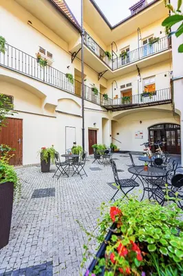 an outdoor patio with tables and chairs and flowers at Josephine Old Town Square Hotel - Czech Leading Hotels in Prague