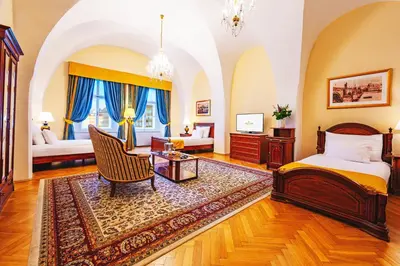 a bedroom with a bed and a chair and a table at Josephine Old Town Square Hotel - Czech Leading Hotels in Prague