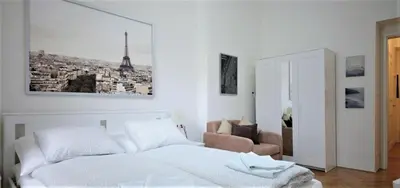 a white bedroom with a bed and a chair at City Castle Aparthotel in Prague