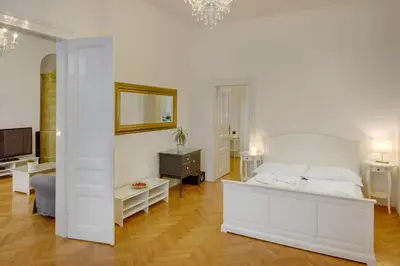 a white bedroom with a bed and a television at Charles Bridge Premium Residence in Prague