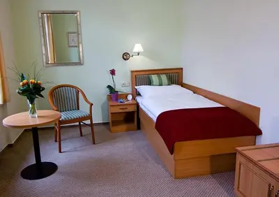 a bedroom with a bed and a table and a chair at Castle Residence Praha in Prague