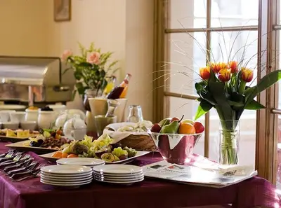 a table with plates of food and flowers on it at Castle Residence Praha in Prague