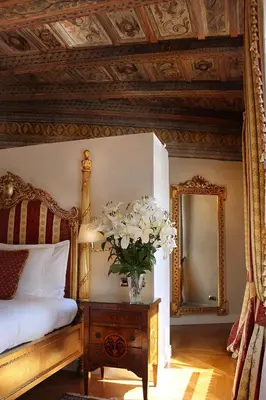 a bedroom with a bed and a vase of flowers on a table at Alchymist Prague Castle Suites Hotel in Prague