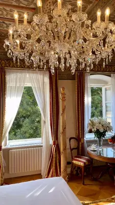 a bedroom with a chandelier and a table and a bed at Alchymist Prague Castle Suites Hotel in Prague