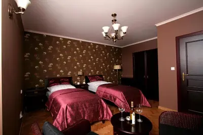 a bedroom with two beds with red sheets and a chandelier at Rezidence Liběchov in Liběchov