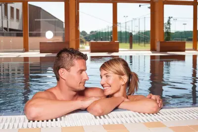 a man and a woman sitting in a swimming pool at Park Holiday Congress & Wellness Hotel in Prague