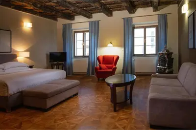 a bedroom with a bed and a couch and a chair at Charles Bridge Heritage Suites by SALVATOR HOTELS in Prague