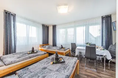 a room with two beds and a table and chairs at Pension Milada in Klecany