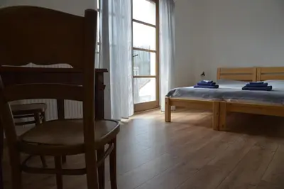 a bedroom with a bed and a chair and a window at Statek Krkavčí Hora in Nižbor