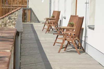 a row of wooden chairs sitting on a balcony at Statek Krkavčí Hora in Nižbor