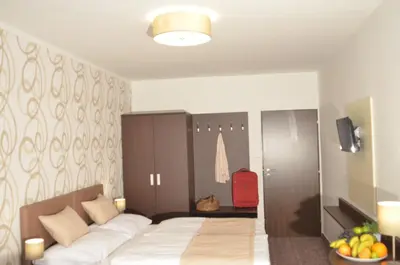 a bedroom with a large bed and a red suitcase at Hotel Atlas in Benešov