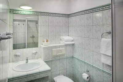 a bathroom with a sink and a toilet and a mirror at Hotel Atlas in Benešov