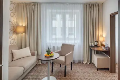 a living room with a couch and a table in front of a window at Hotel Atlas in Benešov