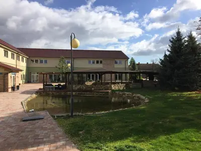 a building with a pond in the yard at Hotel Dvůr in Krnsko