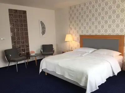 a bedroom with a large bed and two chairs at Hotel Dvůr in Krnsko