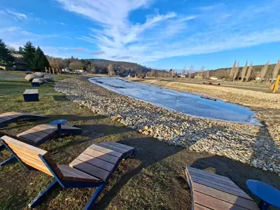 a group of chairs sitting next to a river at Penzion U Švarců in Zduchovice