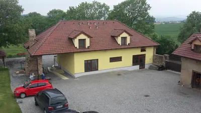 a yellow house with a car parked in a driveway at Penzion AMÁLKA Černín in Zdice