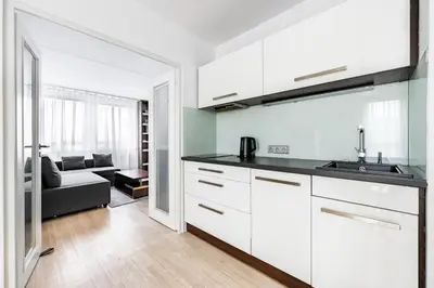 a kitchen with white cabinets and a living room at Family apartment Prague in Prague