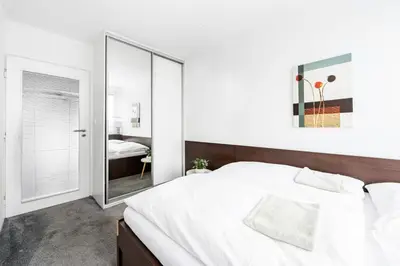 a bedroom with a large white bed and a mirror at Family apartment Prague in Prague