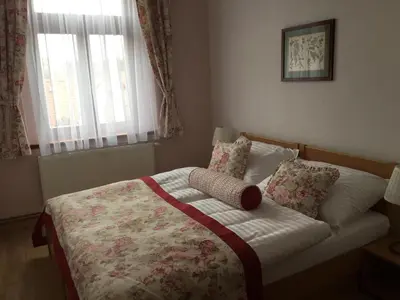 a bedroom with a bed with a floral bedspread and pillows at Penzion Karlštejn in Karlštejn