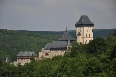 a castle on top of a hill with trees at Penzion Karlštejn in Karlštejn