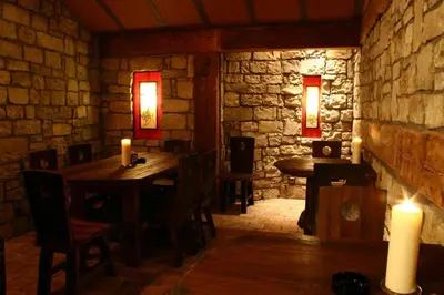 a restaurant with two tables and candles in a stone wall at Zlaty Lev in Louny