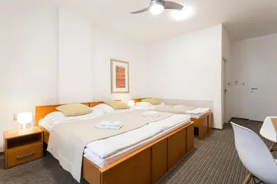 a hotel room with two beds and a chair at Pension Akat in Prague