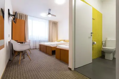 a room with a bathroom with a bed and a toilet at Pension Akat in Prague