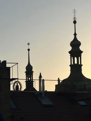 two towers on top of a building with the sun setting at ARTHARMONY Pension & Hostel in Prague