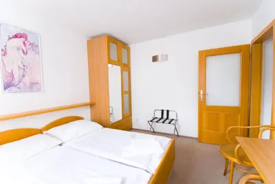 a bedroom with a bed and a table and a chair at Hotel Smaragd in Prague
