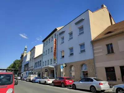 a row of buildings on a street with parked cars at Hotel Koruna in Roudnice nad Labem