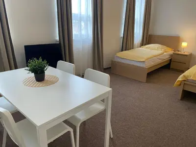 a room with a white table and chairs and a bed at Hotel Koruna in Roudnice nad Labem