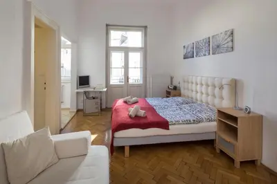 a white bedroom with a bed and a couch at Dušní Apartments in Prague