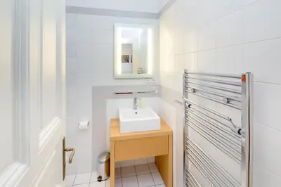 a white bathroom with a sink and a mirror at Dušní Apartments in Prague