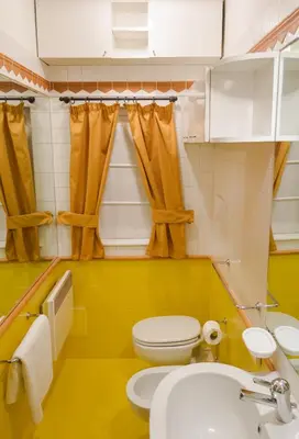 a yellow bathroom with a toilet and a sink at Residence Týnská in Prague