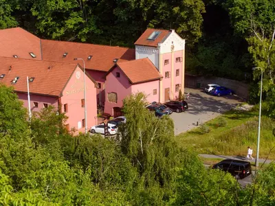 a large pink building with cars parked in a parking lot at Hotel STARÝ PIVOVAR in Prague