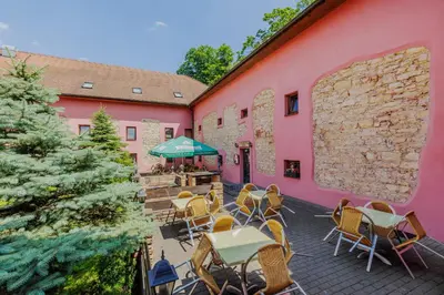 a patio with tables and chairs in front of a pink building at Hotel STARÝ PIVOVAR in Prague