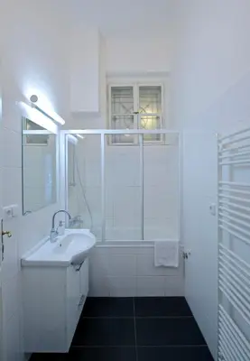 a white bathroom with a sink and a shower at Kafka's Head Apartment in Prague
