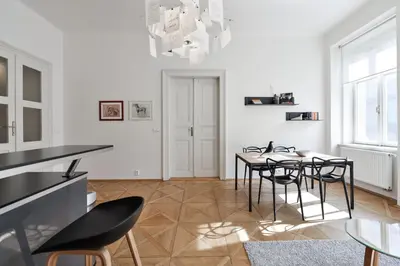 a dining room with white walls and a table and chairs at Kafka's Head Apartment in Prague